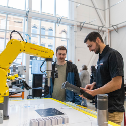 Two people interacting with and talking about a FANUC robot at the Digital Foundry